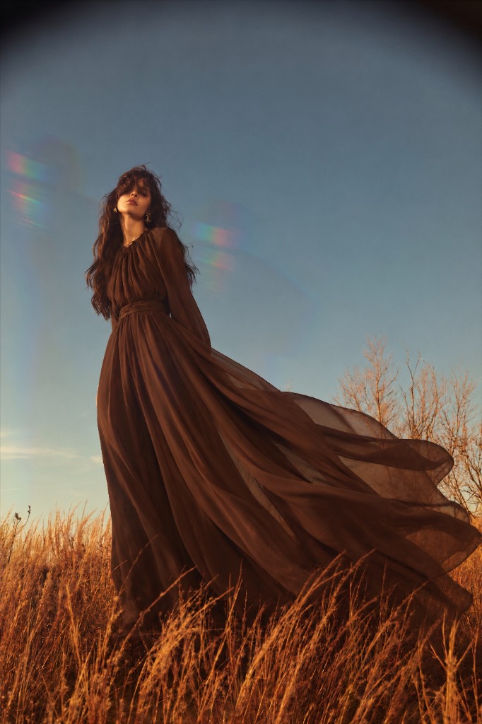 Woman in a long brown dress standing in golden grass